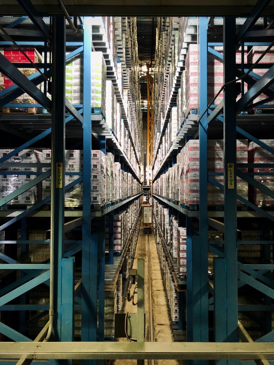 aerial shot of warehouse aisle with tall blue racks full of supplies on either side