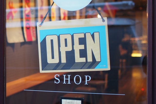 window with blue sign that says open to shop