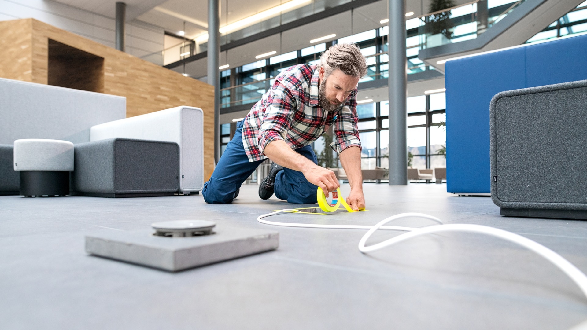 man applying tesa construction tape to floor of newly built building interior