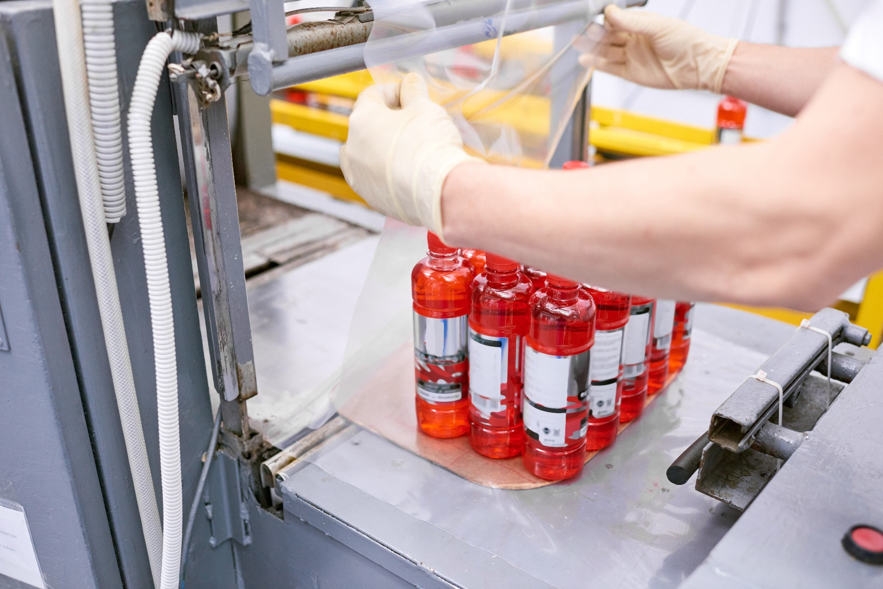 factory-worker-packing-full-bottles-into-plastic-PD2QFUB